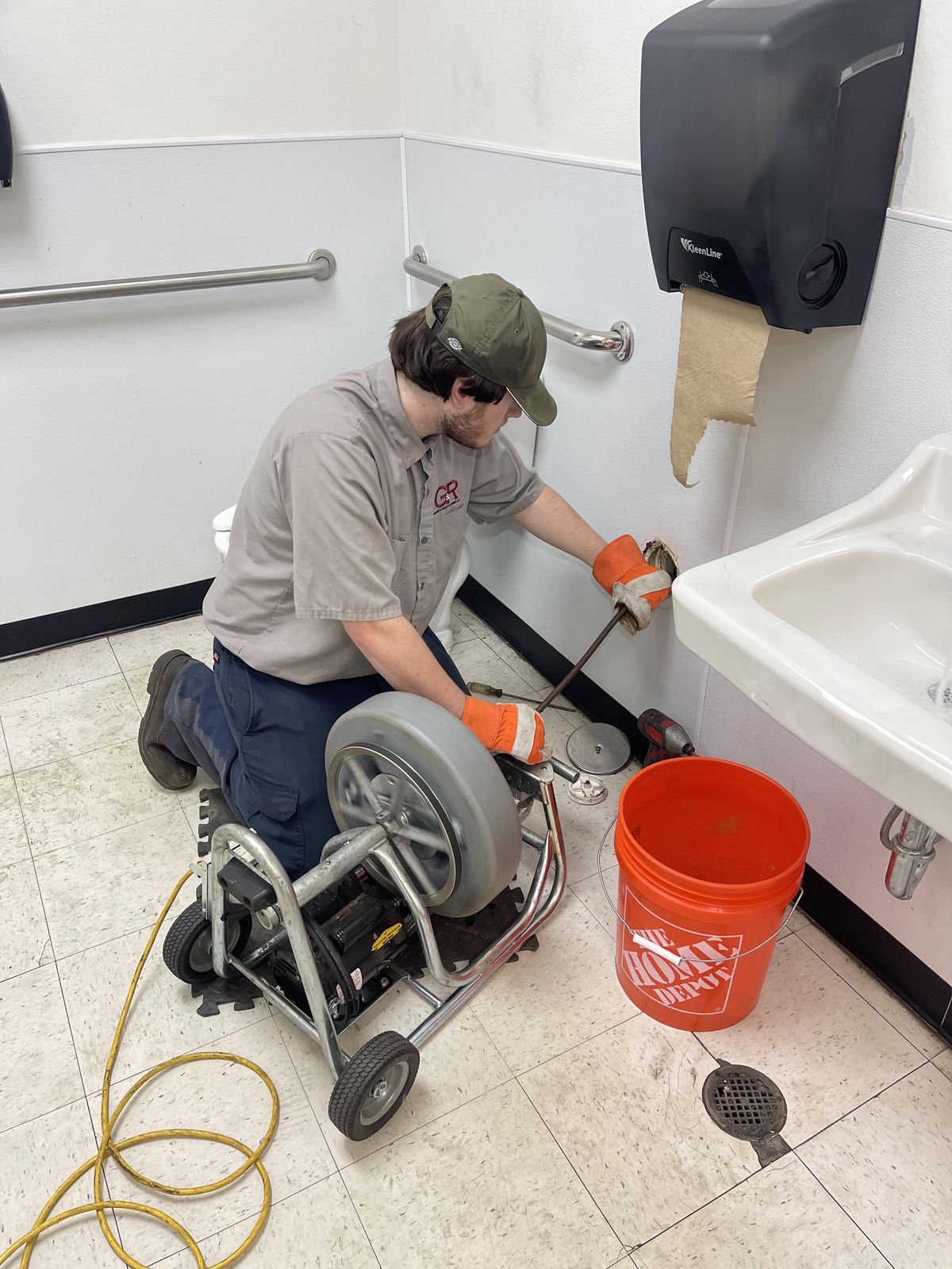 G&R technician running a drain machine in a commercial restroom