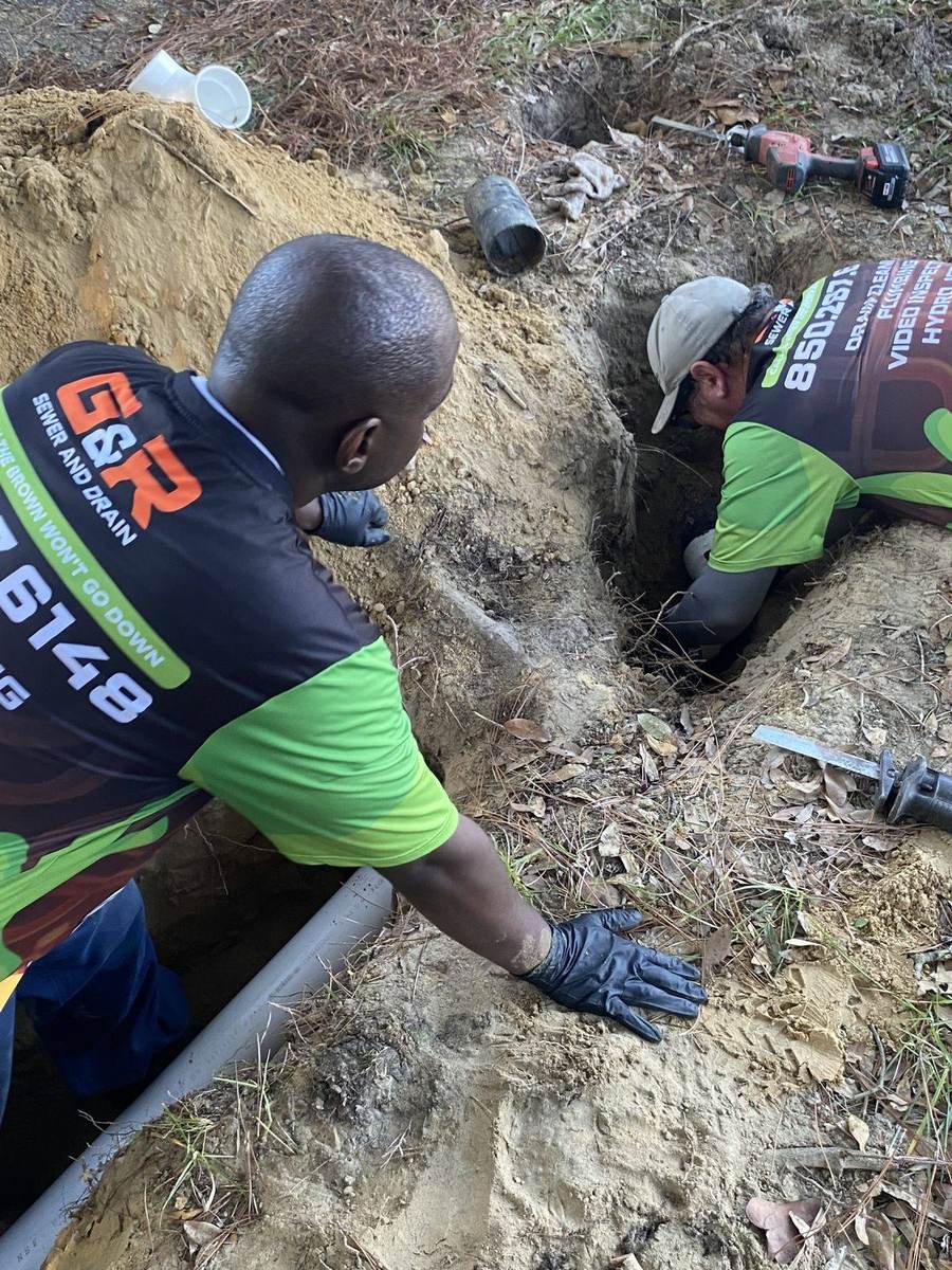 Two G&R technicians repairing a sewer line in a trench